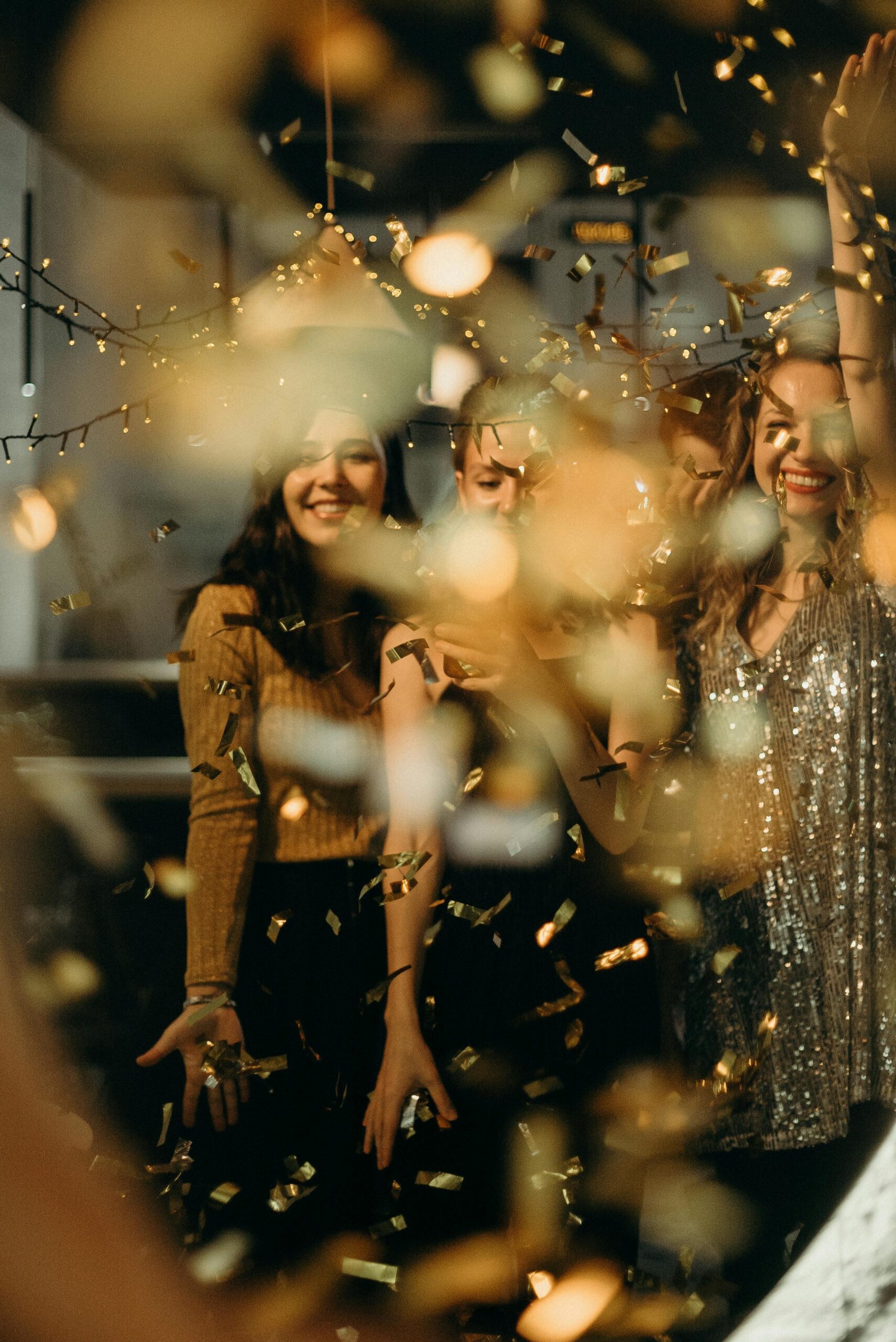 Women celebrating with confetti and string lights, capturing festive joy and excitement.