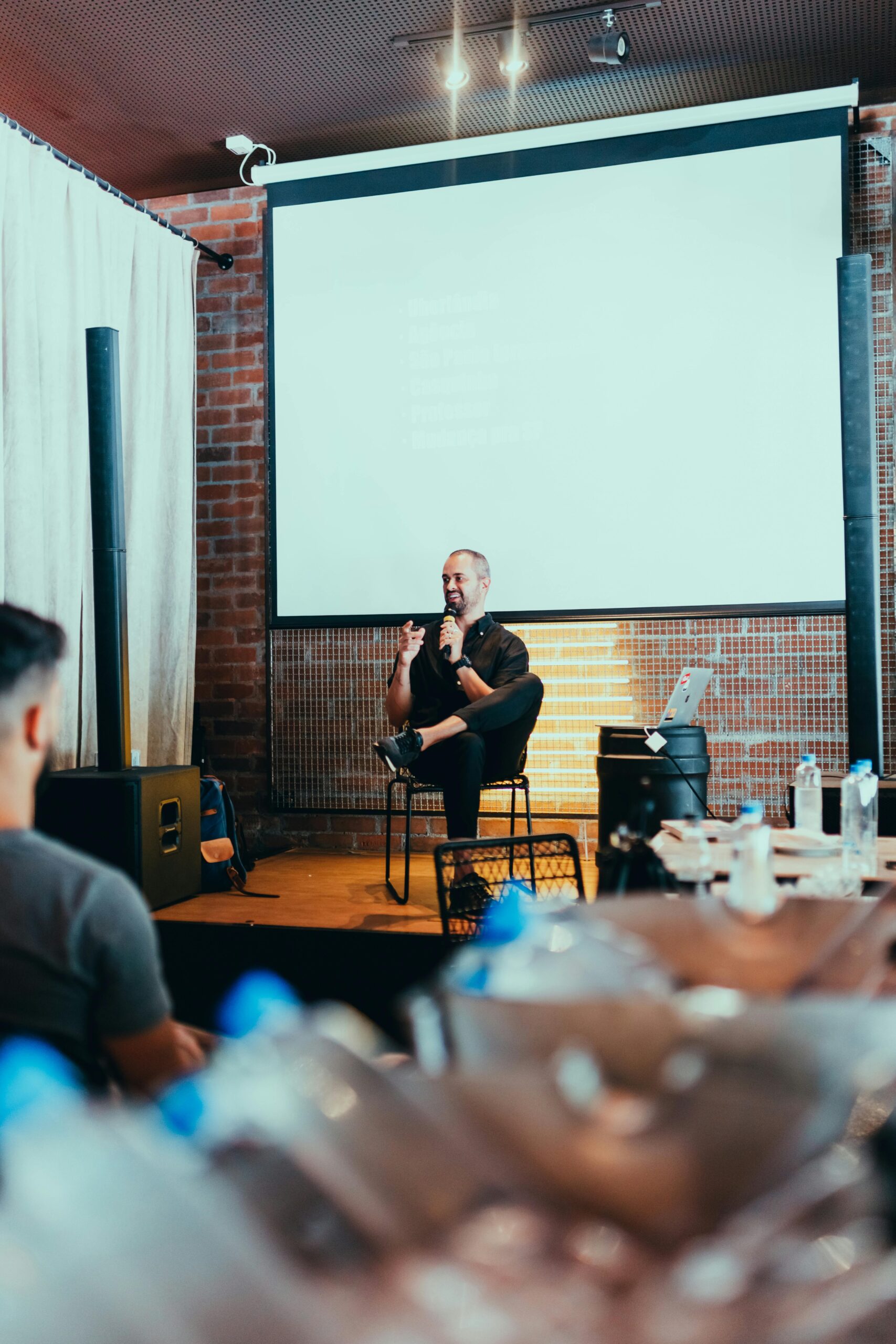 Speaker giving a talk in a cozy conference room with attentive audience.
